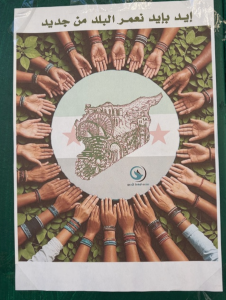 Sur la place al-Karame, dans la ville de Soueïda, affiche portant l’inscription: avec nos mains, nous construisons le pays à nouveau (photo J. Daher, janv. 2025)